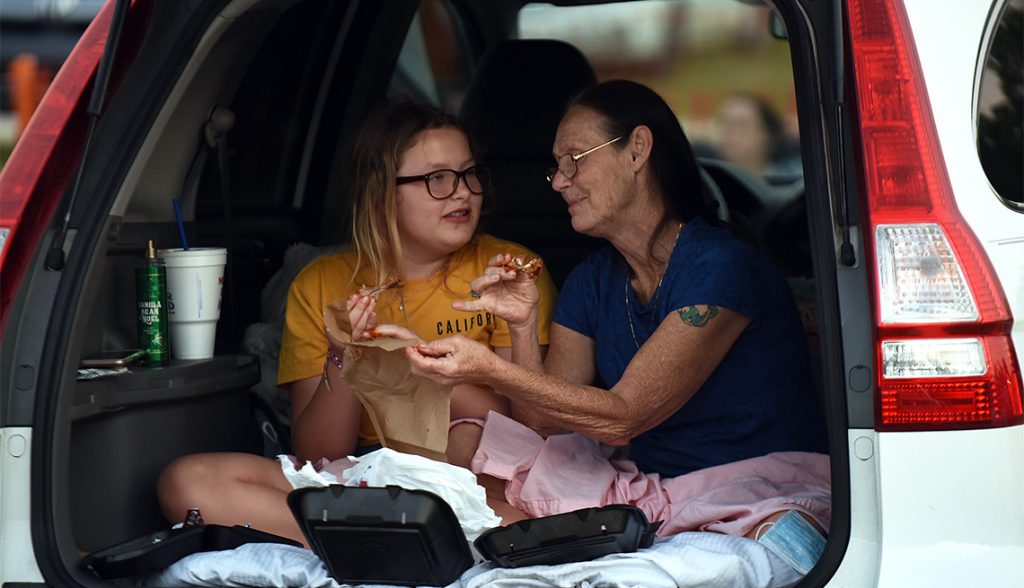 Imagen de dos mujeres que comen palomitas en la parte trasera de un auto mientras esteran a que empieza la pelicula