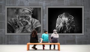 Personas en un banco mirando cuadros tristes