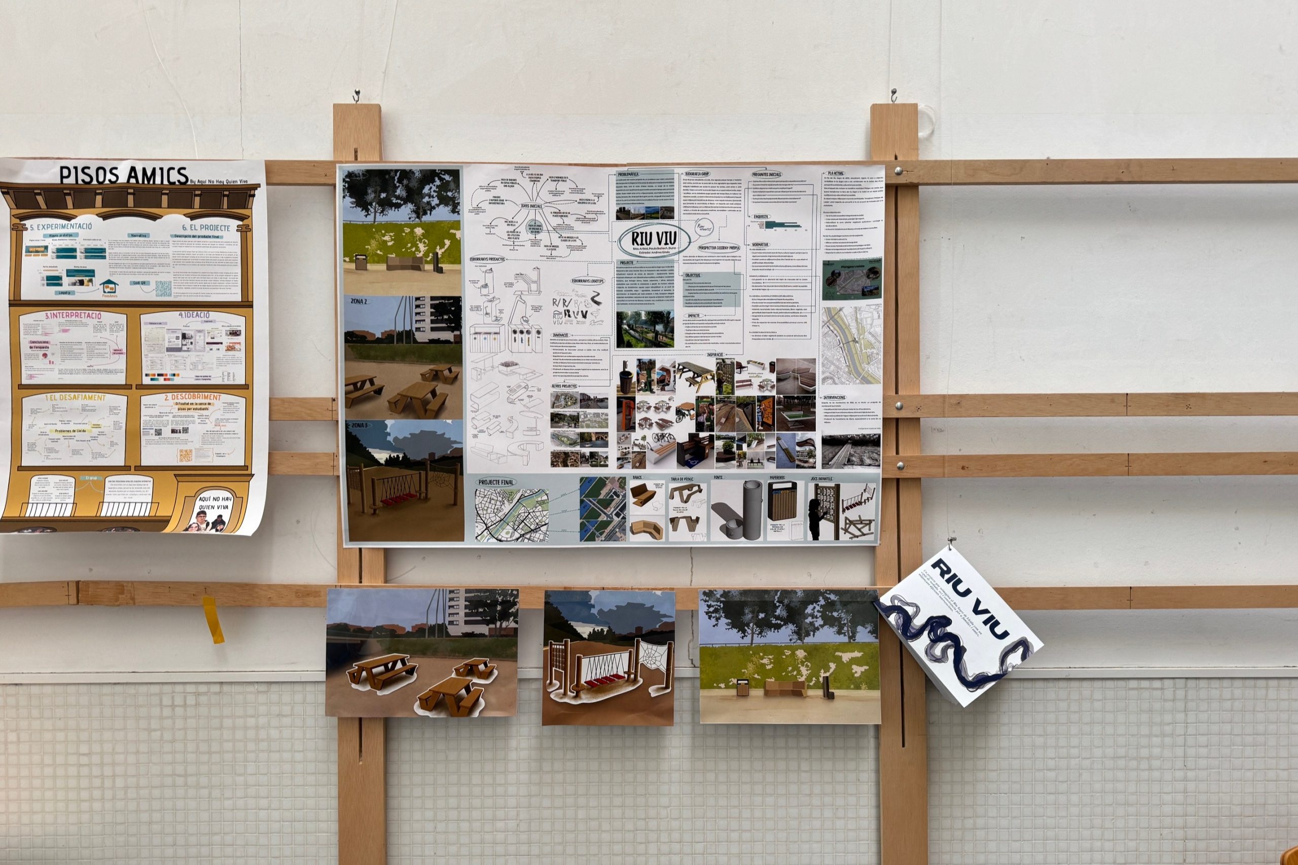Exposició de projectes en una paret amb llistons de fusta. La imatge mostra un projecte anomenat “RIU VIU”, amb plànols, esquemes, renders de mobiliari urbà i informació gràfica. El conjunt transmet una presentació acadèmica o professional de disseny urbà o arquitectura.