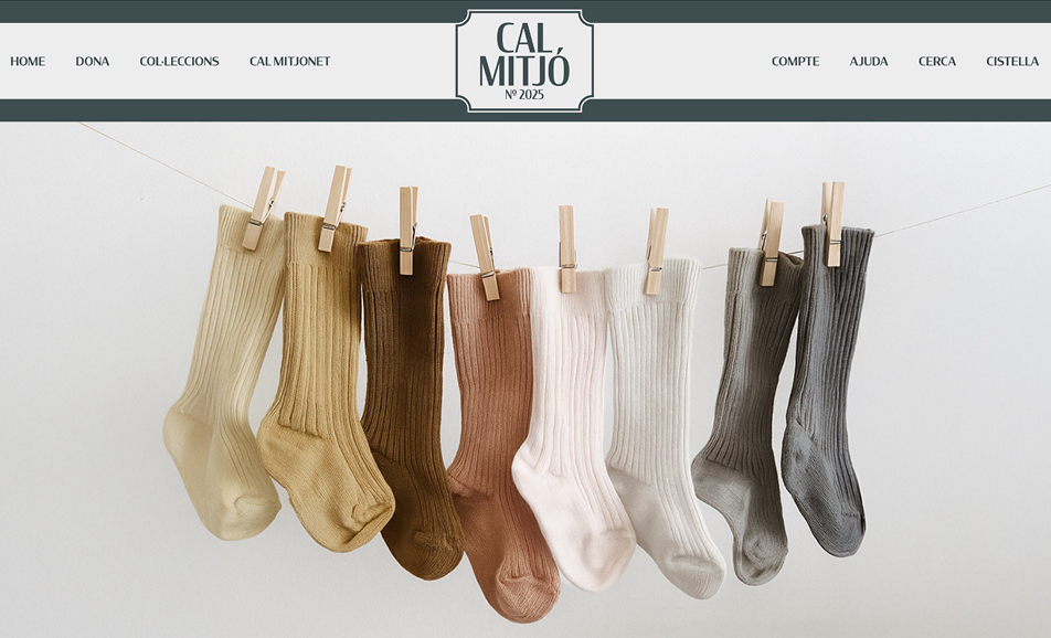 Captura de pantalla de la pàgina web de Cal Mitjó, botiga de mitjons. Es veu la capçalera amb el logo 'CAL MITJÓ Nº 2025' i el menú de navegació. A la imatge principal, una corda amb molts mitjons de colors (beix, marró, blanc i gris) penjats amb pinces de fusta.