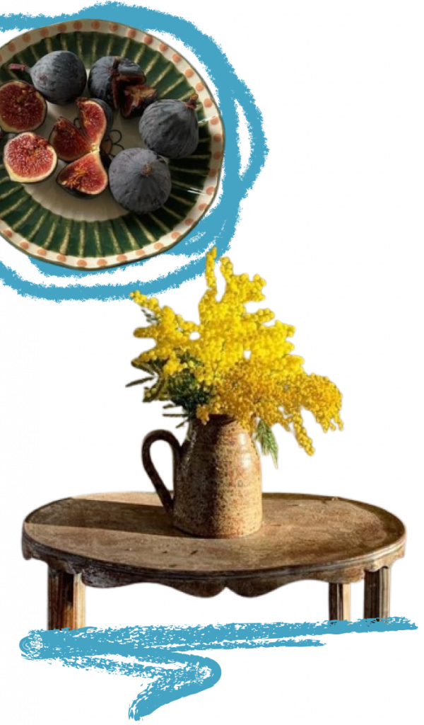 Plat amb mangranes i jerro de flors amb una tauleta de fusta 