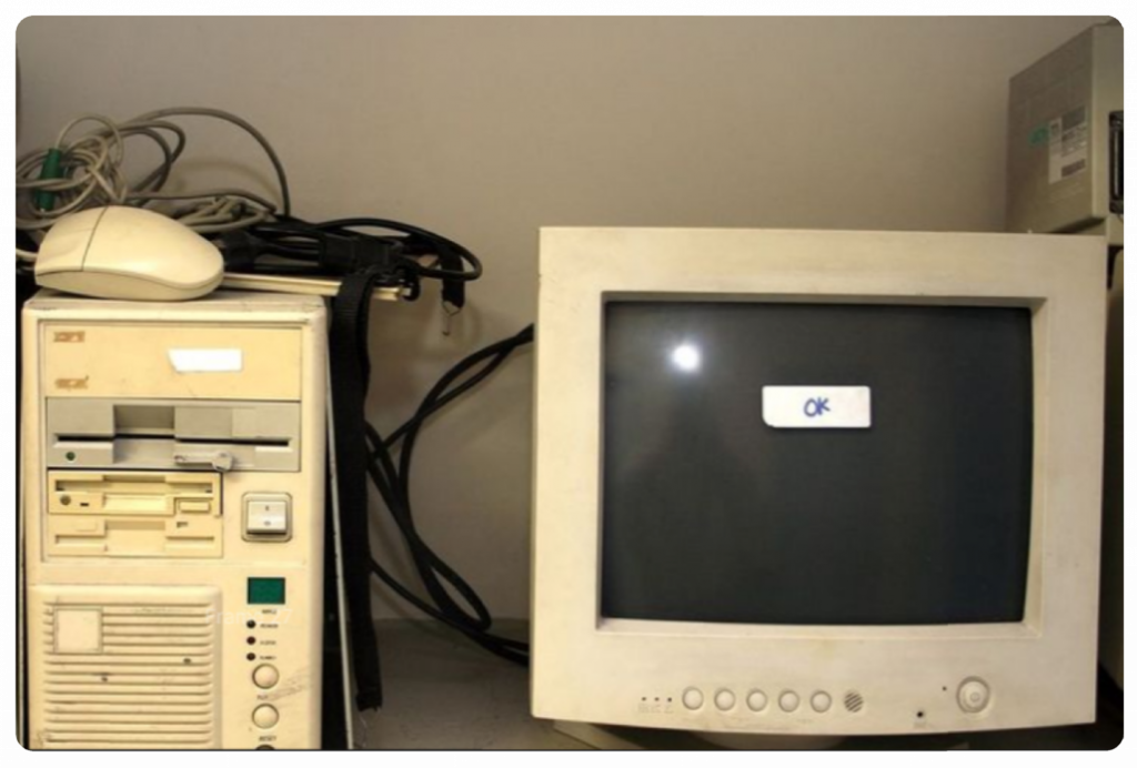 Fotografía de un ordenador antiguo, con un post it en pantalla en el que se ve "OK".